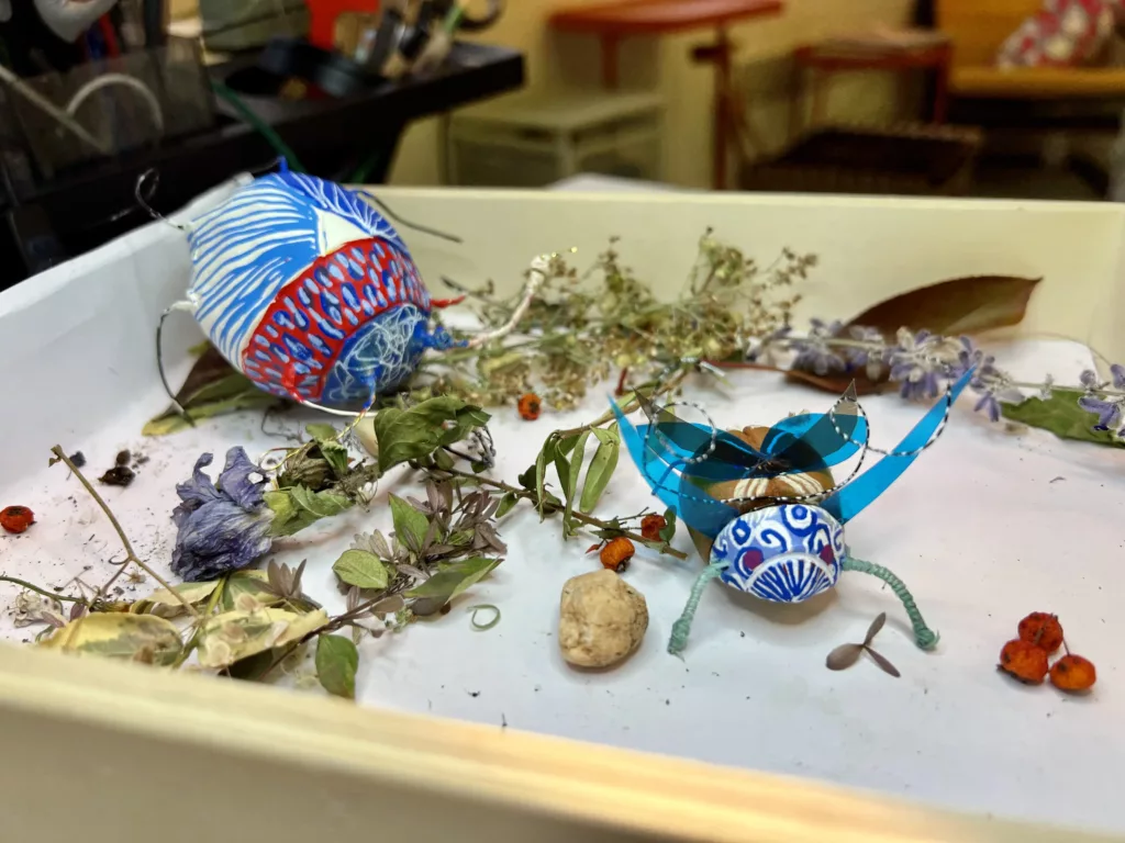 Atelier enfants : insectes en argile terminés présentés dans un décor végétal