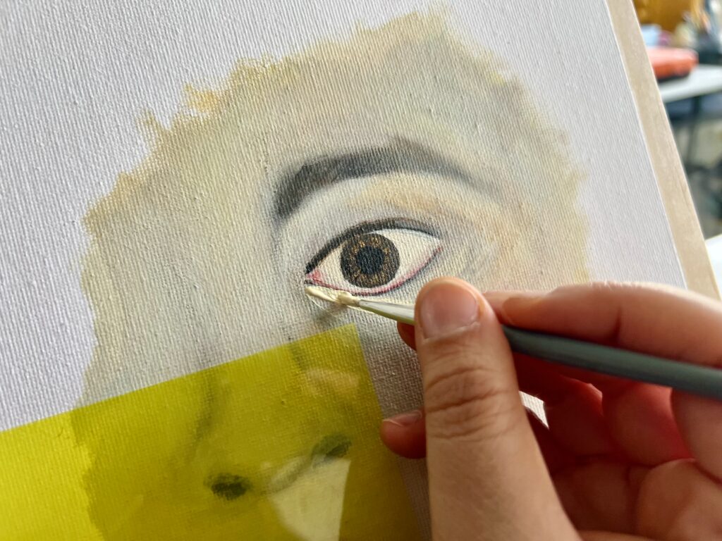 Peinture d’un visage en détail avec pinceau dans la main de l’artiste